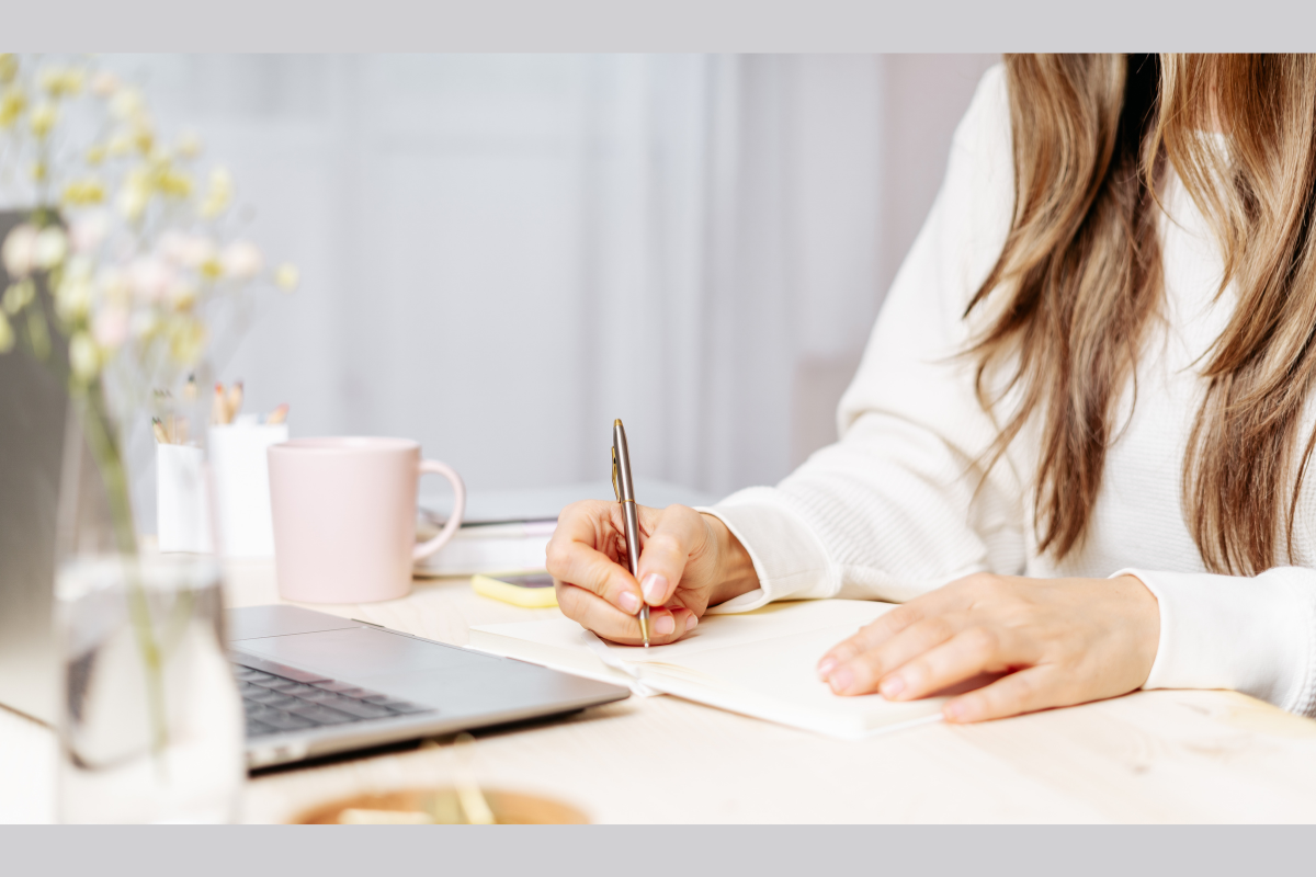 Therapist taking CPD accredited online neurodiversity training, writing notes beside laptop and coffee mug.